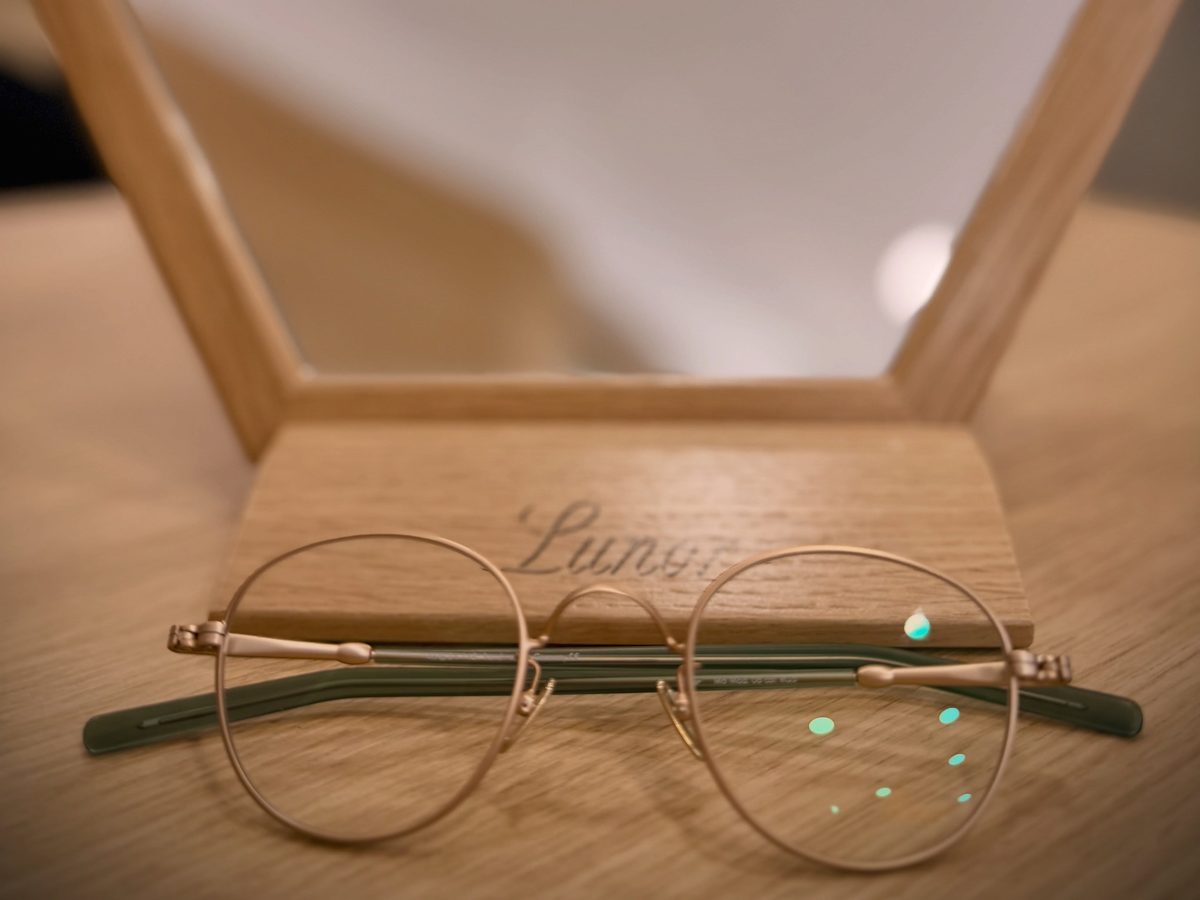 Handgefertigte Metallbrille auf einem Holzaufsteller