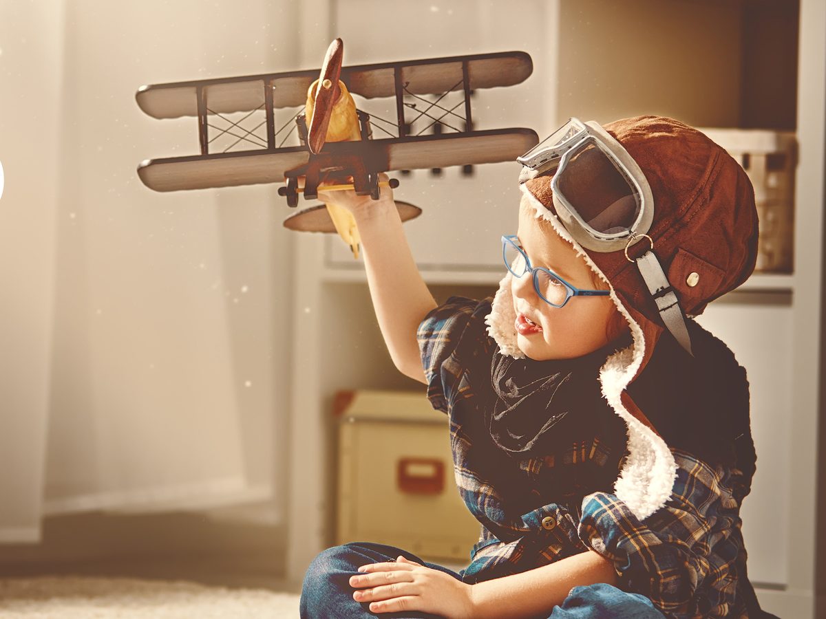 Kind mit Brille spielt mit einem Spielzeugflugzeug